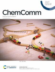 The front cover of ChemComm, showing toy trains. The tracks pass under two bridges and then merge, to represent that the same product is produced via two different pathways.