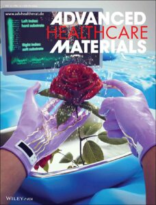 A cover art for Advanced Healthcare Materials. The cover shows a hand holding a flower in an operating theater. The gloves are covered by sensors to detect the softness or hardness of the tissue.